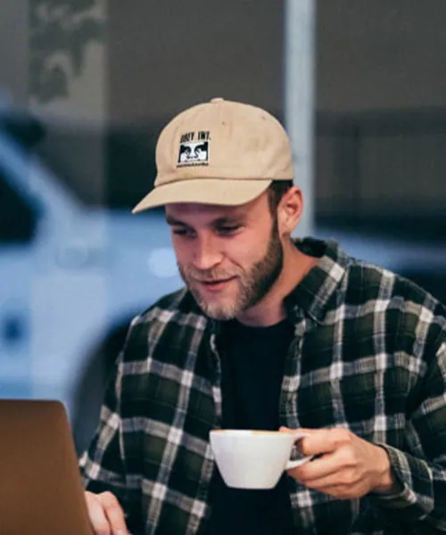 A business owner relaxed with a coffee at his laptop